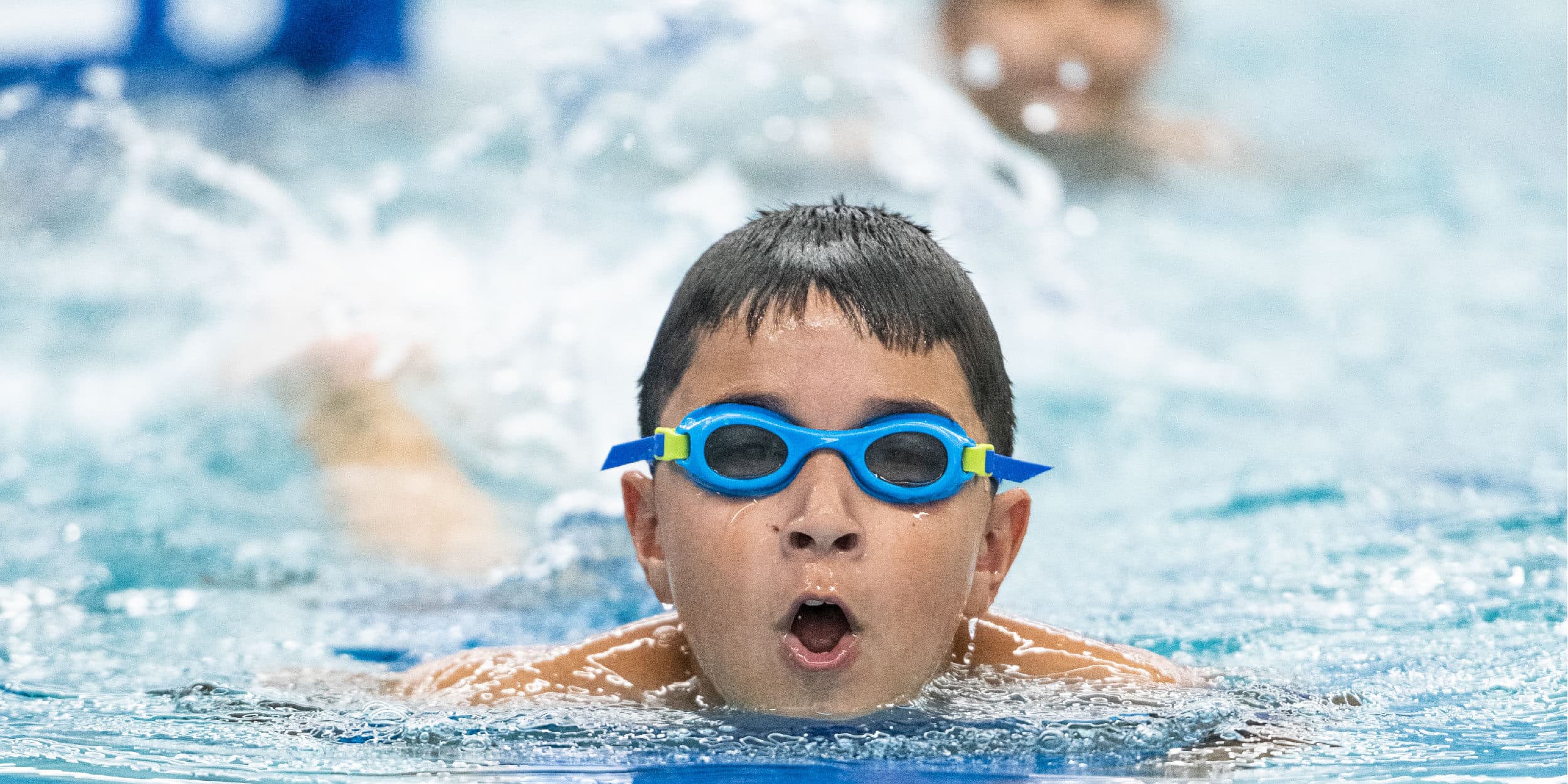 boy wearing googles swimming breast stroke at pedalheads