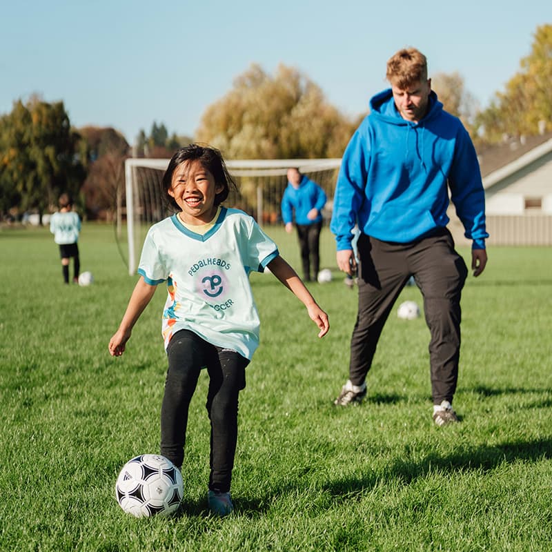 Pedalheads Soccer girl kicking ball with instructor